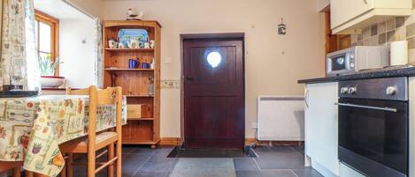 A kitchen with a dining area, wooden cabinets, a microwave, and a stove.