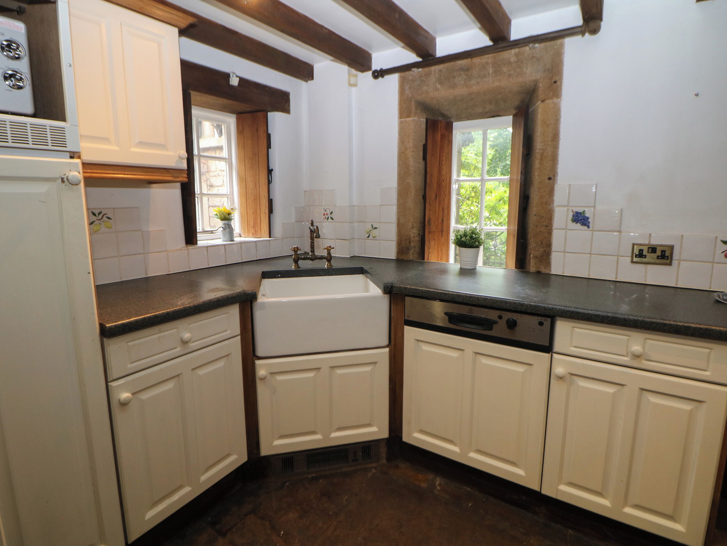 A kitchen with white cabinets, a built-in oven, and a window with a view of greenery.