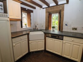 Cocina con armarios blancos, horno empotrado y ventana con vista a follaje.