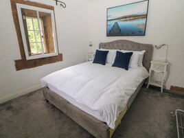 Un dormitorio con una cama grande, una ventana, un cuadro y una mesita de noche.