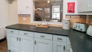 A kitchen with white cabinets, a window, a red fire blanket, and two electric toasters. - 3 Nixon Terrace (Maryport)