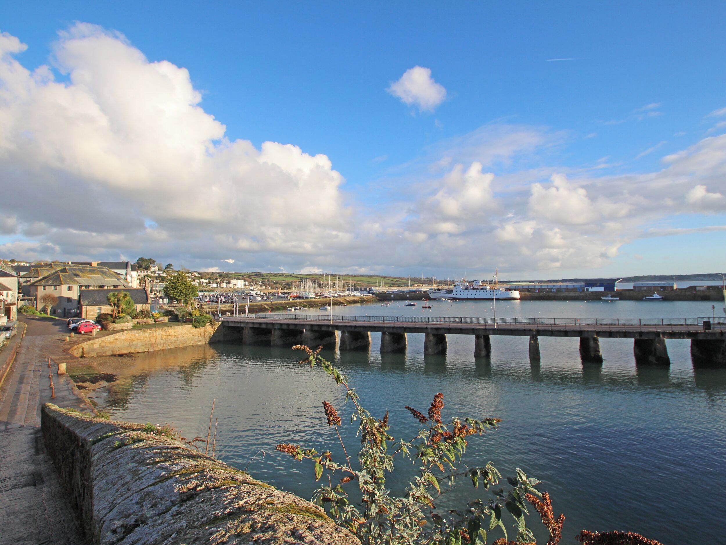 A coastal town with a bridge over water, boats, and a marina.
