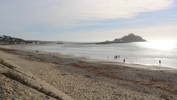 A beach with a distant hill and a clear sky. - Up Over Head (Penzance)