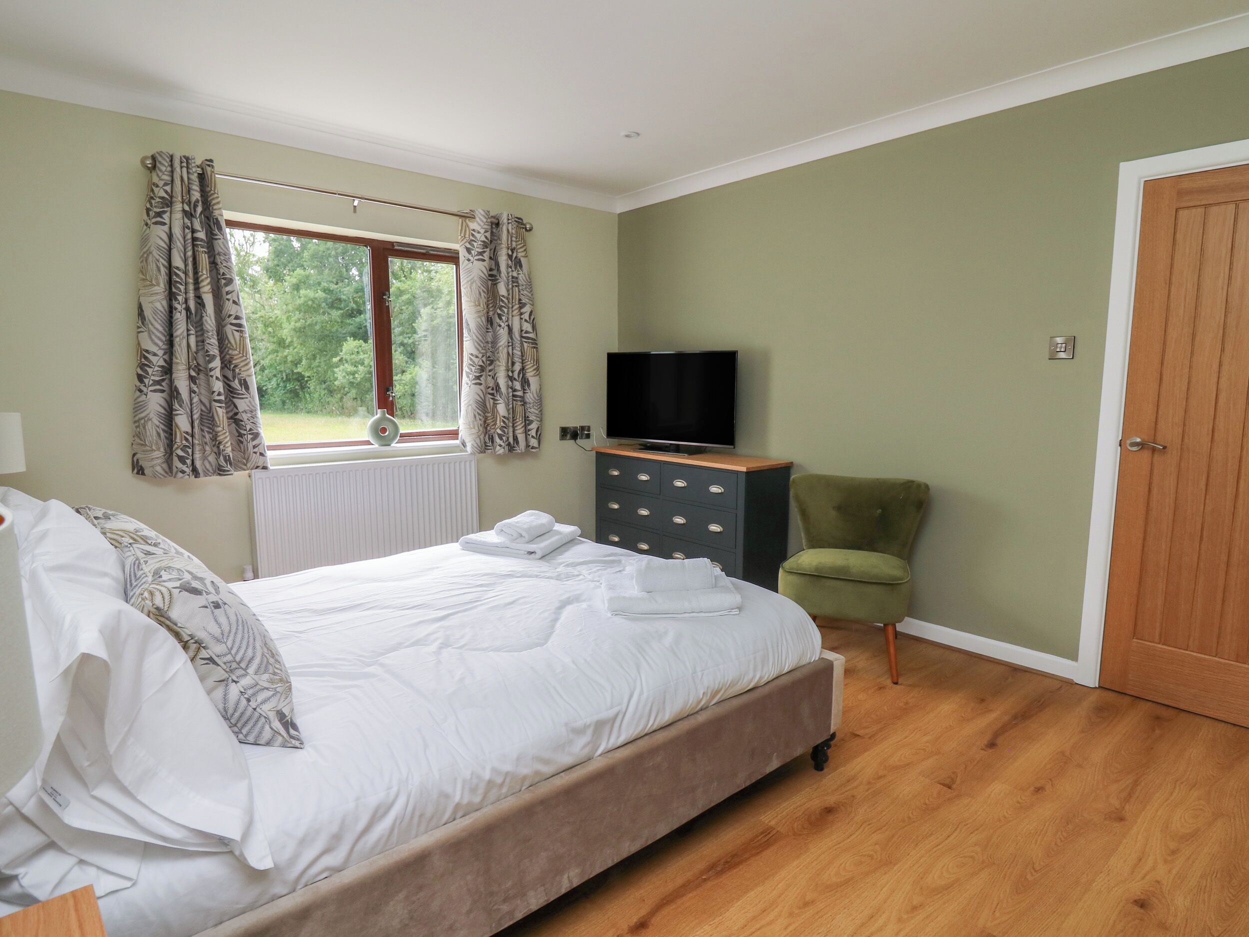 Een slaapkamer met een bed, een kaptafel, een televisie en een stoel.