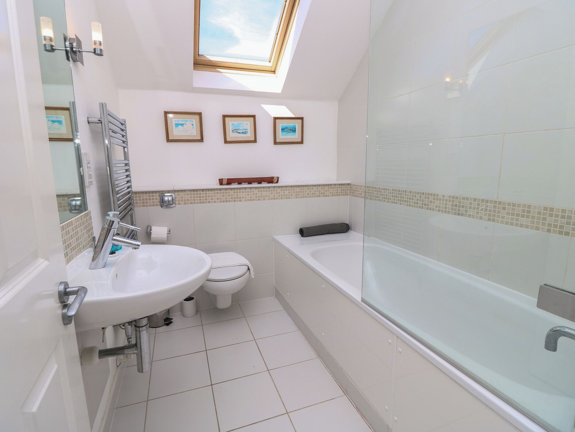 Un baño moderno con tragaluz, bañera, ducha e inodoro.