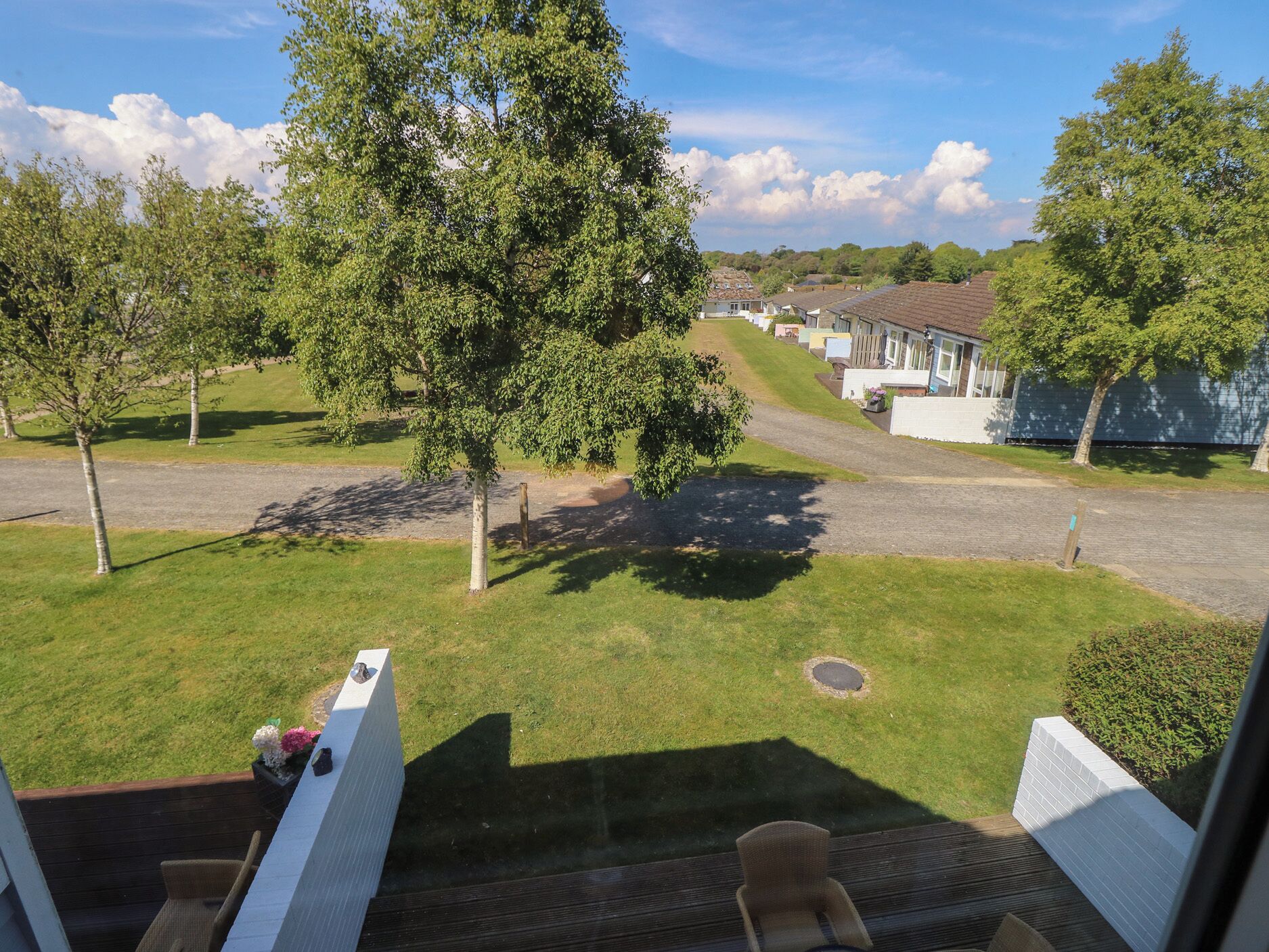 Een woonwijk met een gazon, bomen en een rij huizen.