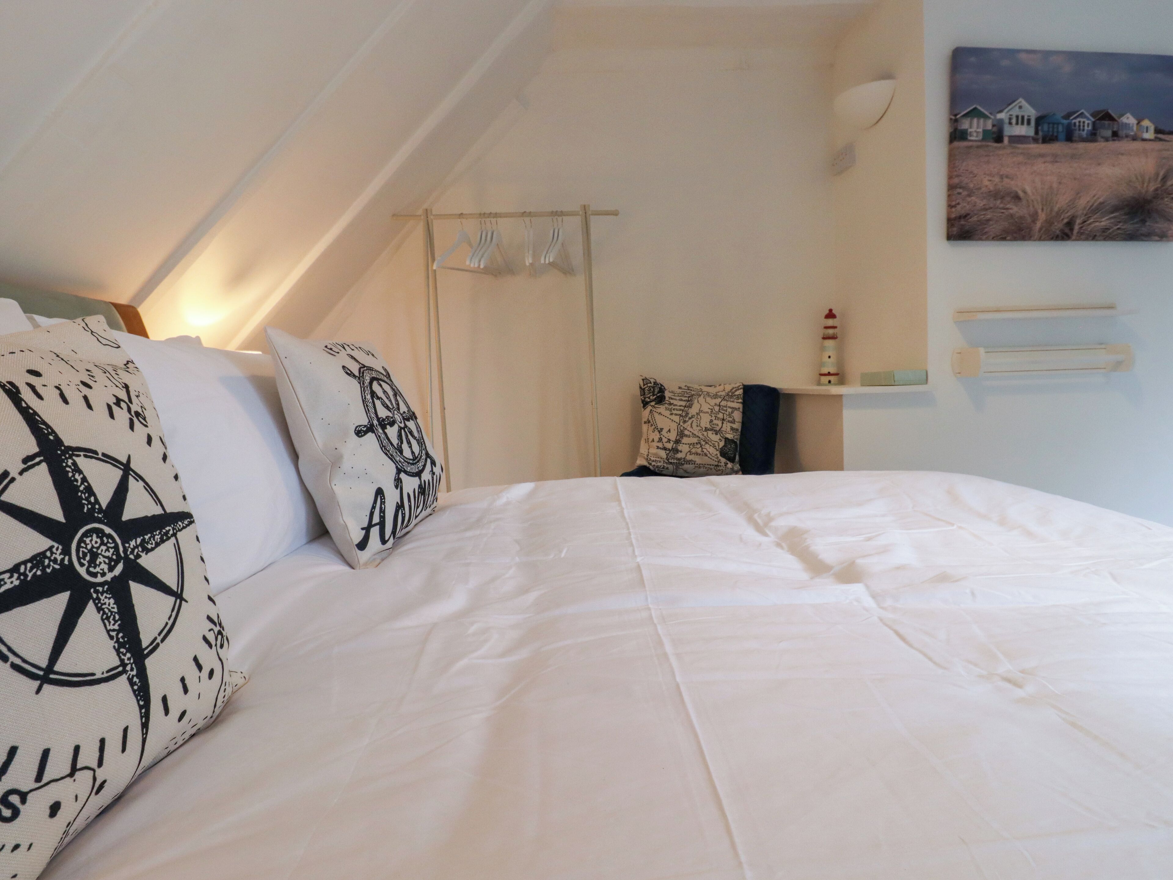 A bedroom with a bed, pillows, a map pillow, a wall-mounted shelf, and a painting.