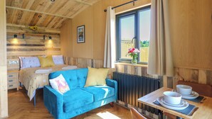 Une pièce confortable avec un lit, un canapé bleu, une table avec des tasses et une fenêtre avec des rideaux.
