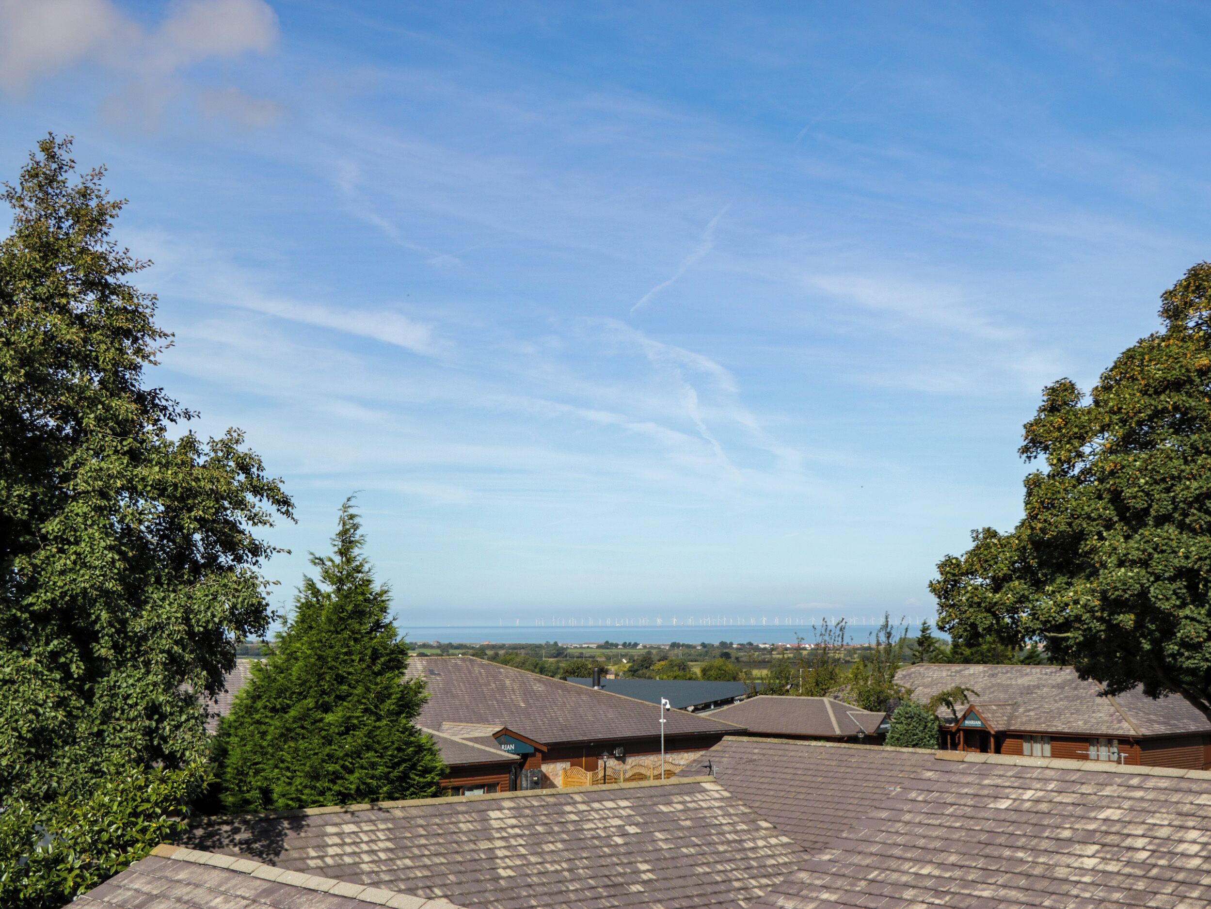 A residential area with multiple houses, a clear sky, and a distant view of the sea.