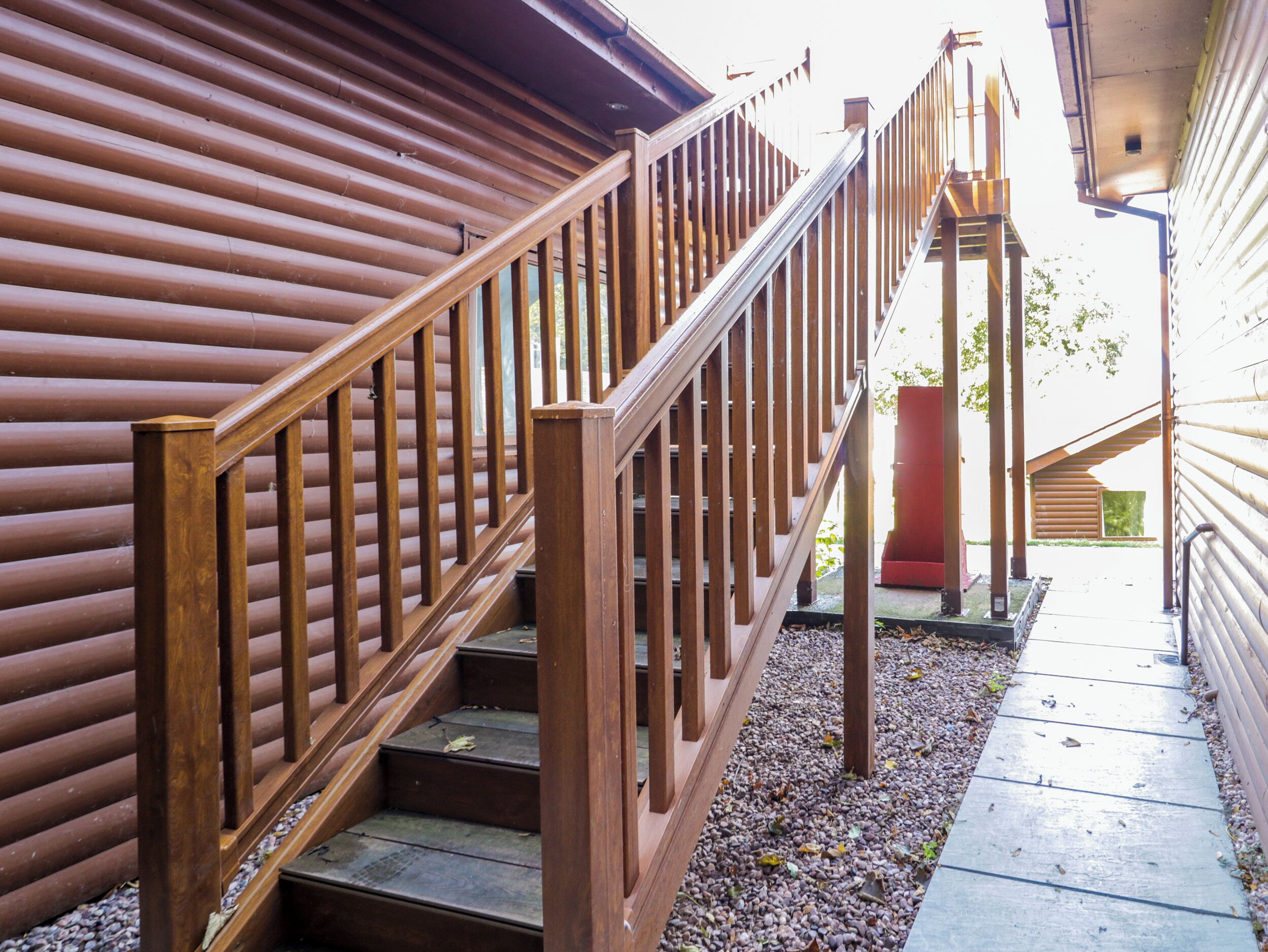A wooden staircase with a metal handrail leading to a covered outdoor area.