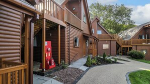 Een rij vakantiehuisjes in blokhutstijl met houten balkons en een grindpad.