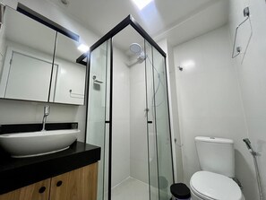 A modern bathroom with a glass-enclosed shower, a white sink, and a toilet. - Hyde Park Comfort 1 (Joao Pessoa)