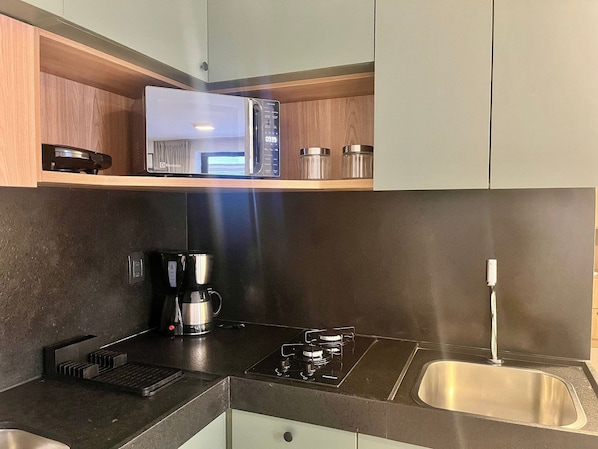 A modern kitchen with a microwave, coffee maker, and stainless steel sink.