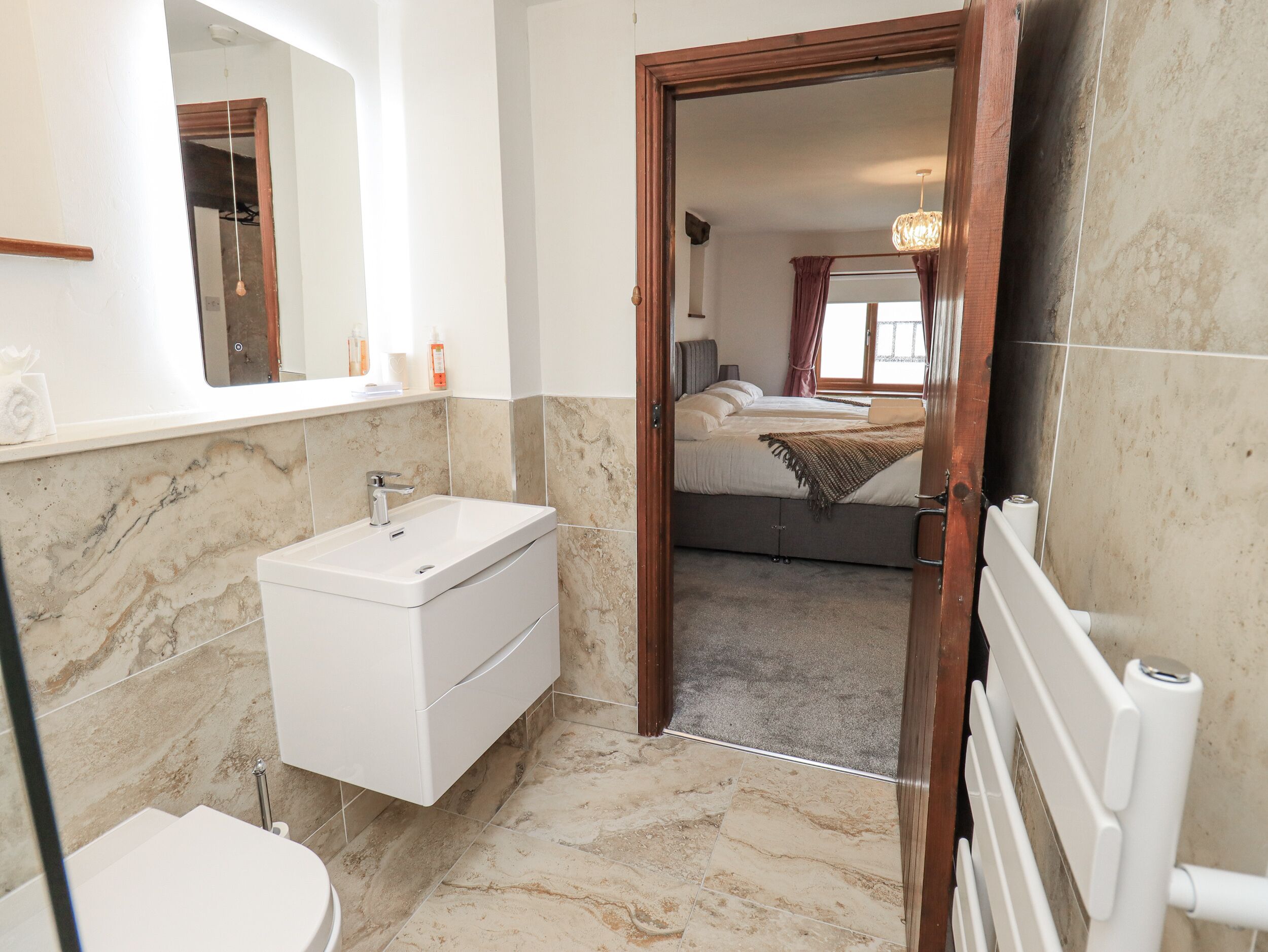 Une salle de bain moderne avec un lavabo en marbre, des toilettes et un espace douche.