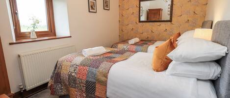 A bedroom with a large bed, a window with a view, a radiator, and a patterned wallpaper.