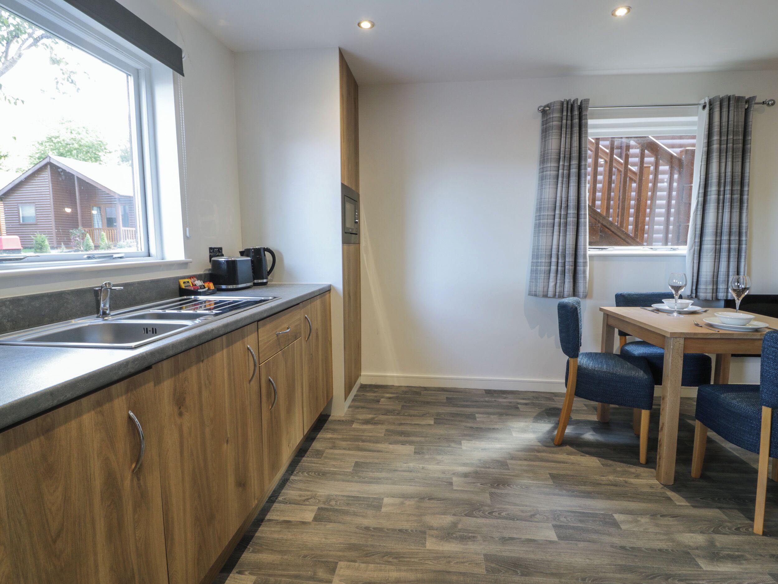 A modern kitchen with a built-in oven, a sink, and a dining area with a table and chairs.