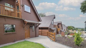 Un bâtiment de style cabane en bois, doté d’un balcon, d’une allée en gravier et d’une clôture en bois.