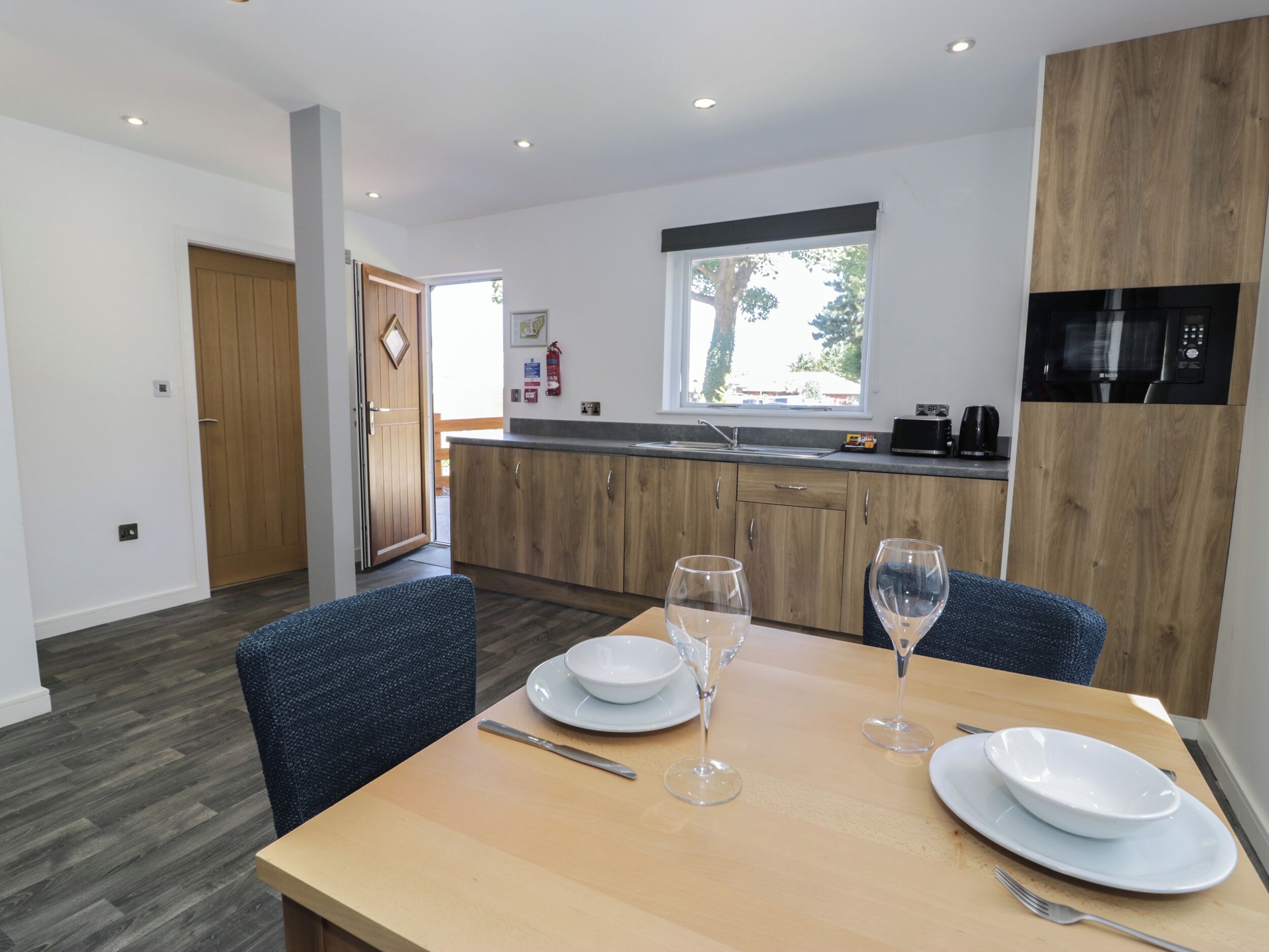 A modern kitchen with wooden cabinets, a built-in microwave, and a window above the sink.