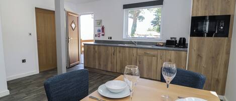 A modern kitchen with wooden cabinets, a built-in microwave, and a window above the sink.
