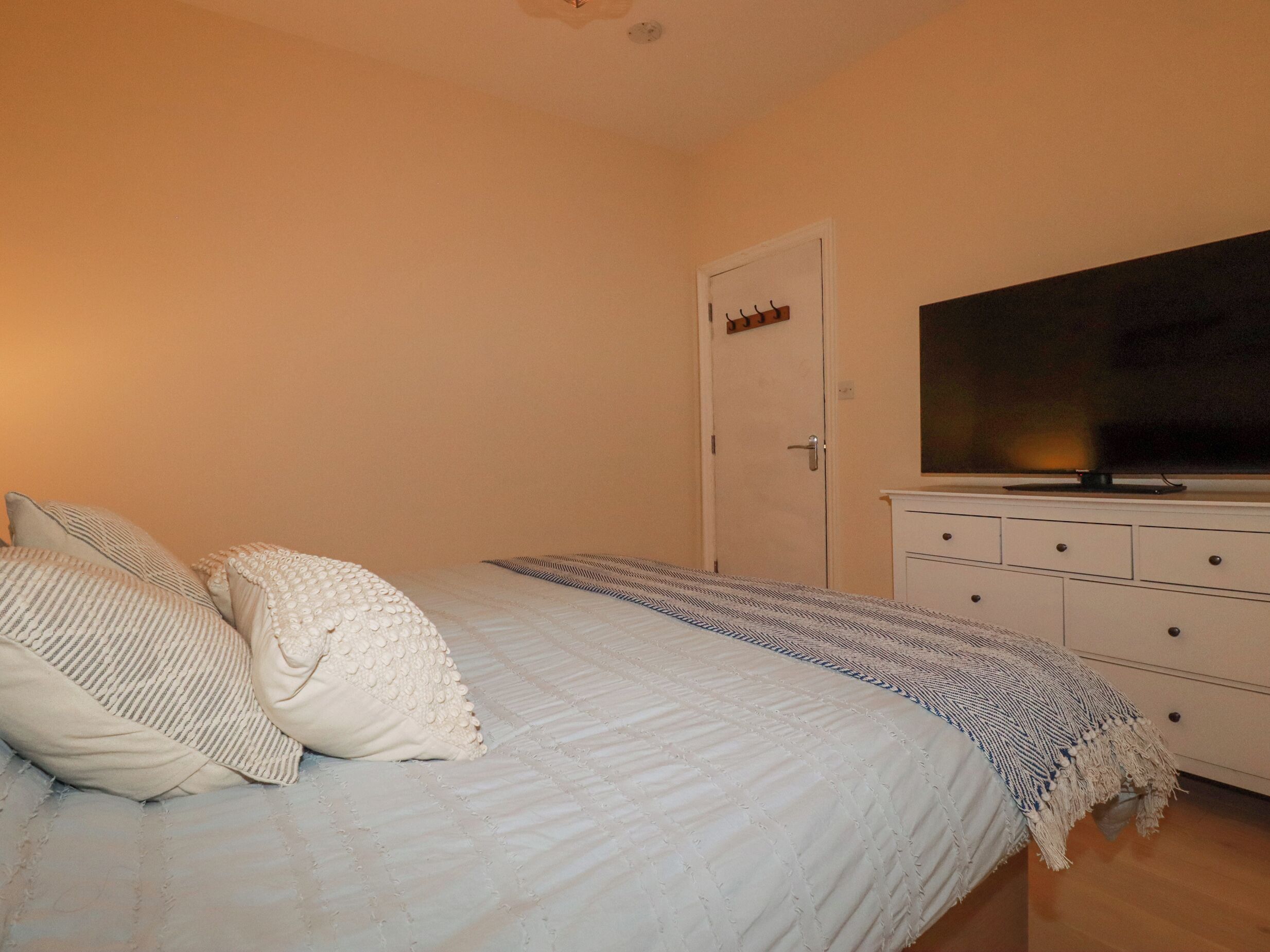 A bedroom with a bed, pillows, a TV, and a dresser.