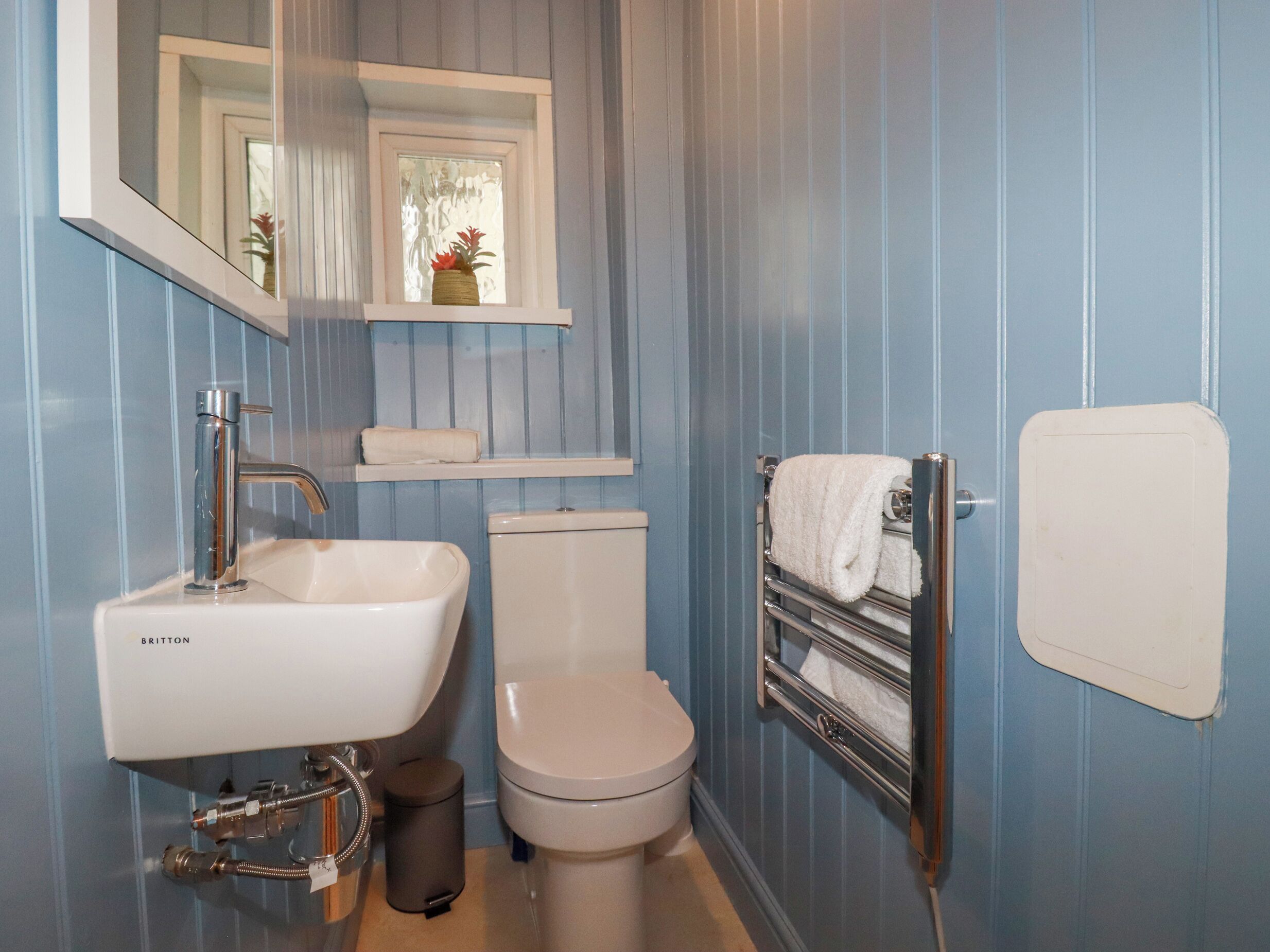 A bathroom with a white sink, a toilet, a mirror, and a towel rack.