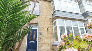 A stone house with a dark blue door, a bay window, and a small porch. - Serendib Cottage (Newquay)