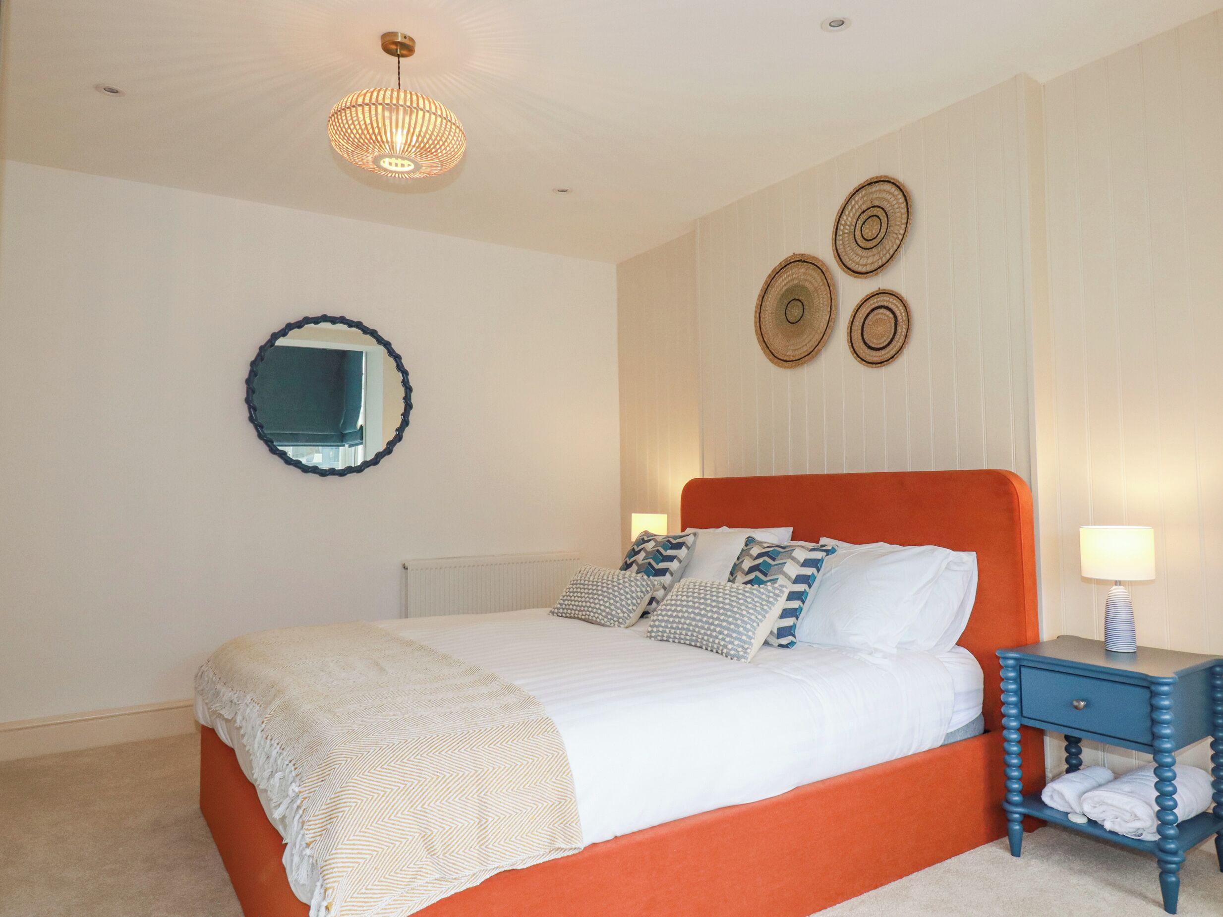 Une chambre à coucher avec un grand lit, une table de chevet, un miroir et des éléments de décoration murale.