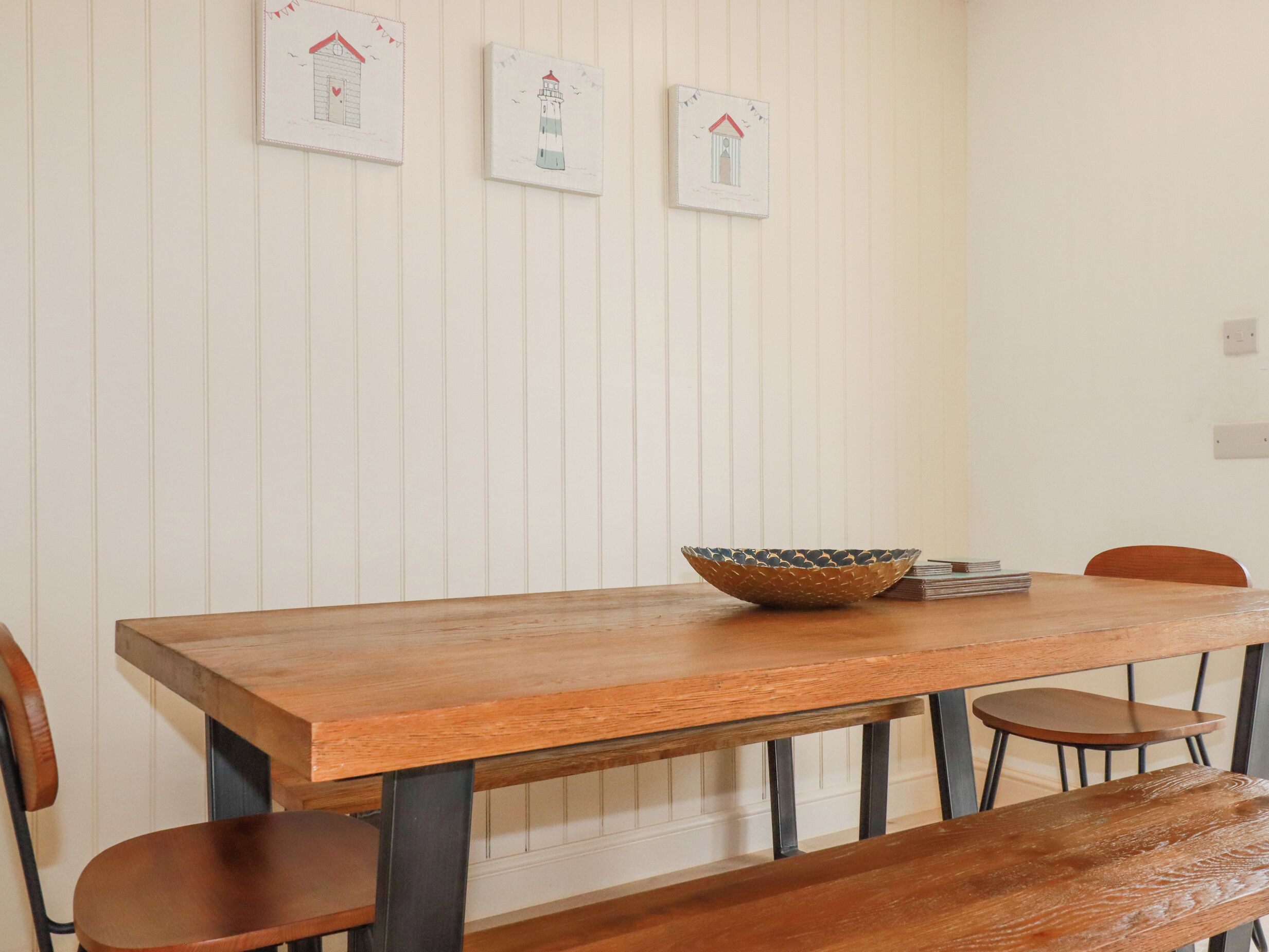 A wooden dining table with a woven bowl, surrounded by wooden chairs.