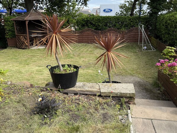 A garden with potted plants, a wooden structure, and a hedge. - The Furness Haven (Barrow-in-Furness)