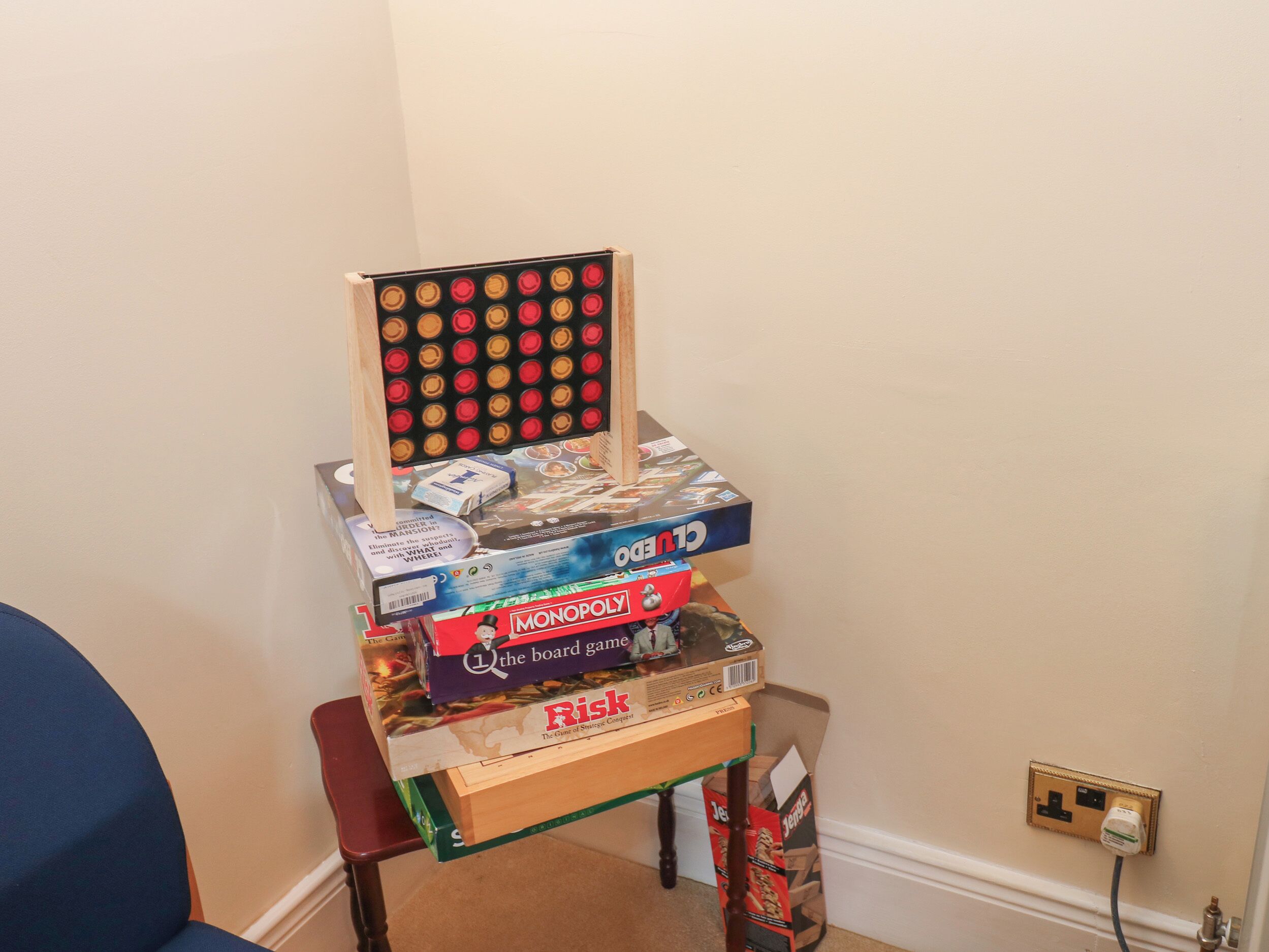 A stack of board games on a small table against a wall.