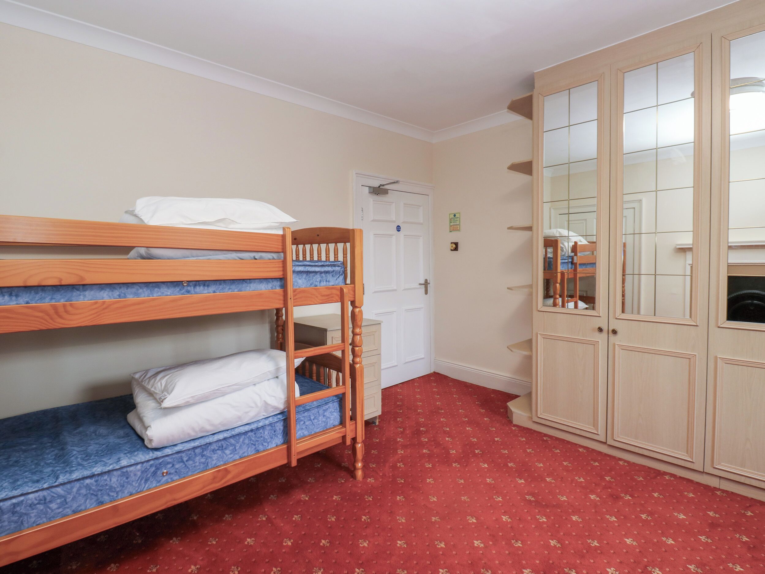 Una habitación con literas, un armario y una puerta.