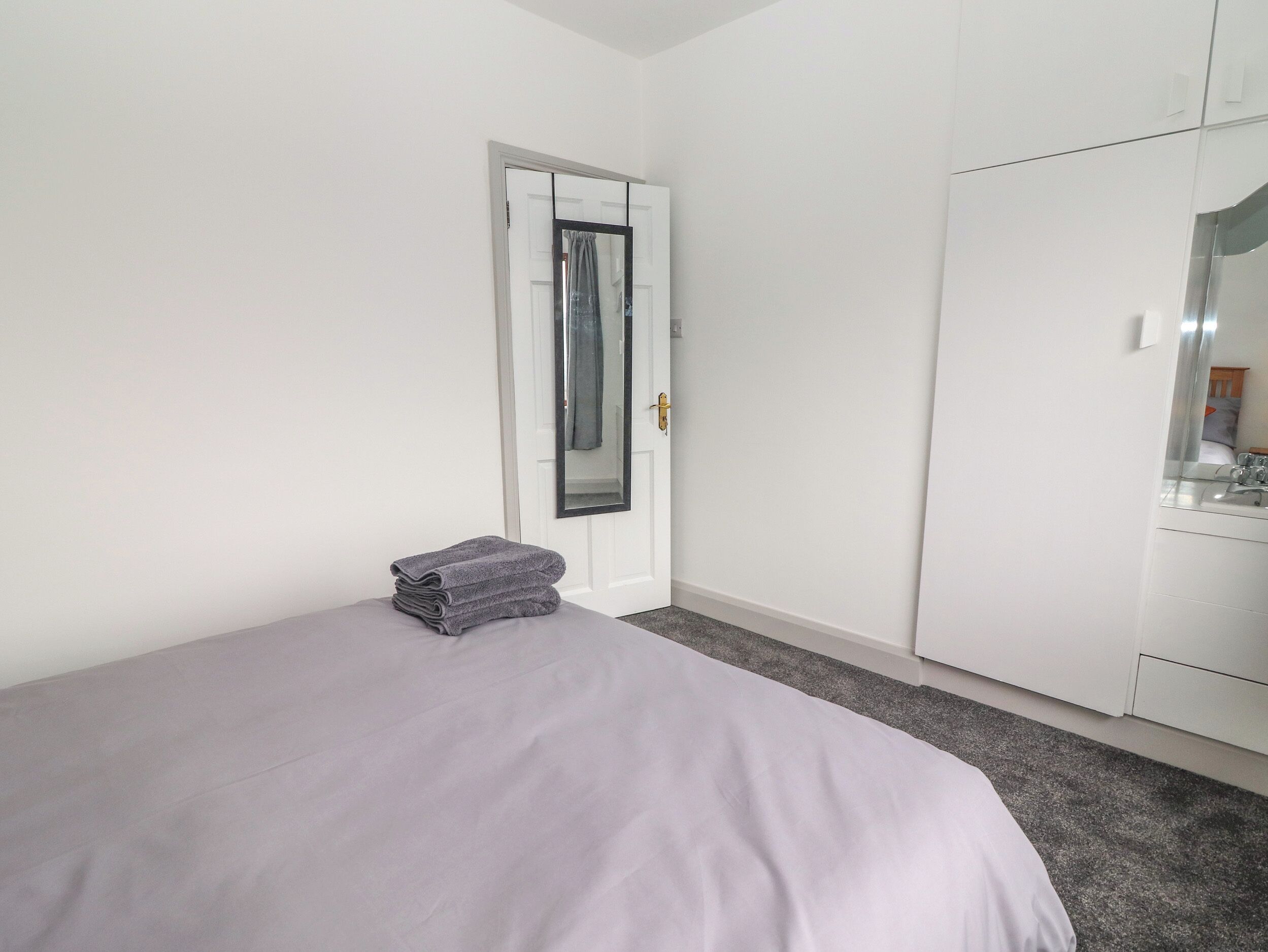 A bedroom with a bed, a wardrobe, and a door with a mirror.