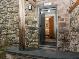 A stone exterior wall with a wooden door leading to a room.
