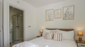 Una habitación de hotel con cama, dos lámparas de noche, ducha y tres cuadros decorativos.