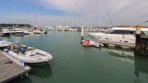 Ein Yachthafen mit verschiedenen Schiffen, einer Holzsteganlage und ruhigem Wasser.