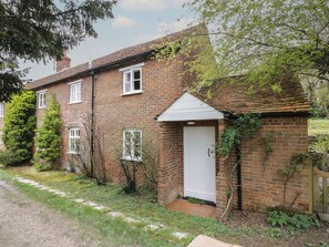 A two-story brick house with a white door and windows, surrounded by greenery and a gravel path. - Chalkpit Cottage (Didcot)