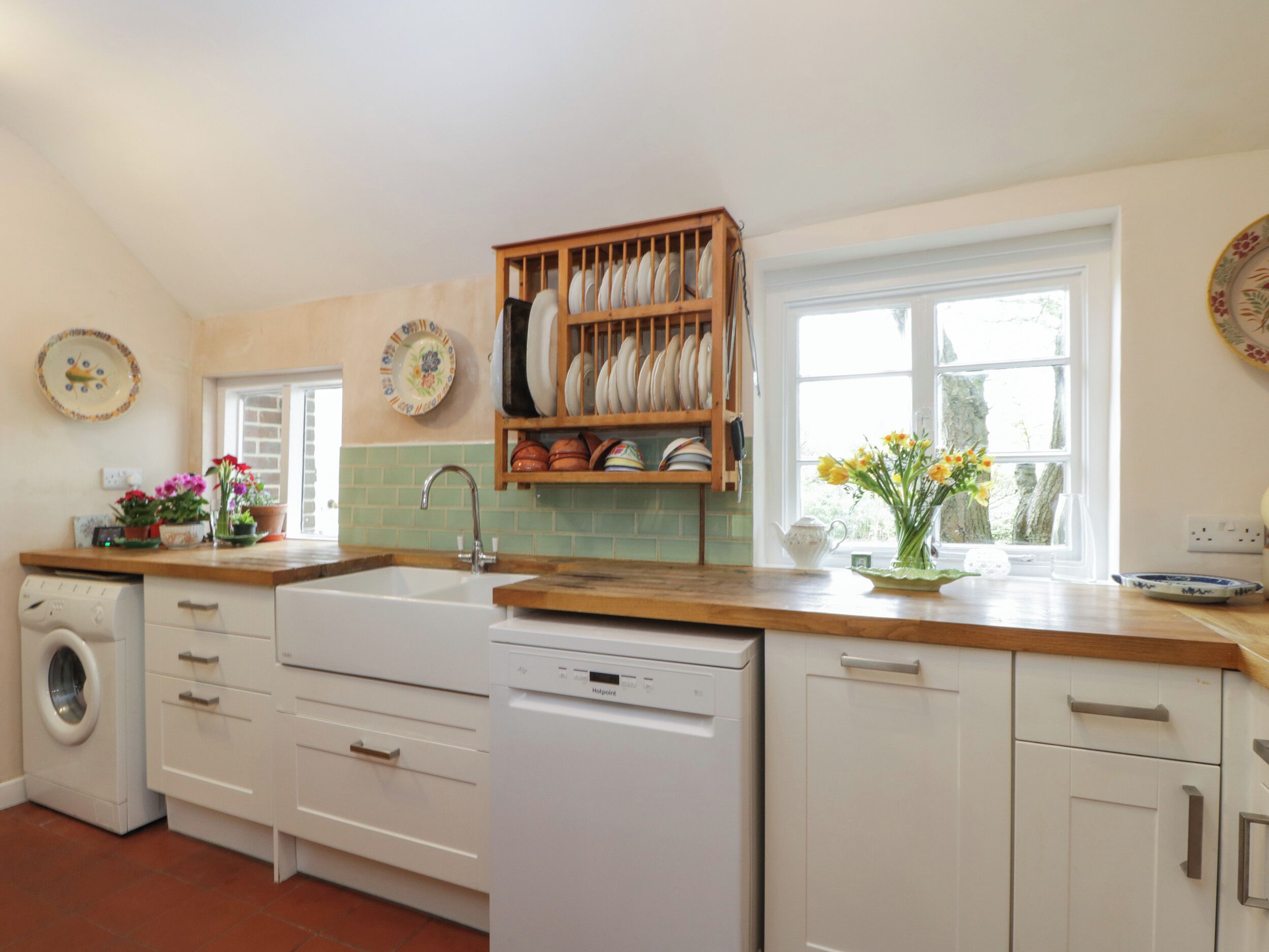 A kitchen with a dishwasher, a washing machine, a sink, and a dish rack.