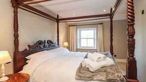 A four-poster bed with a white bedspread and a fluffy throw blanket. - Luham Cottage (Penrith)