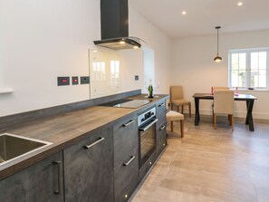 Cozinha moderna com uma ilha grande, forno embutido e um espaço de refeições com mesa e cadeiras.