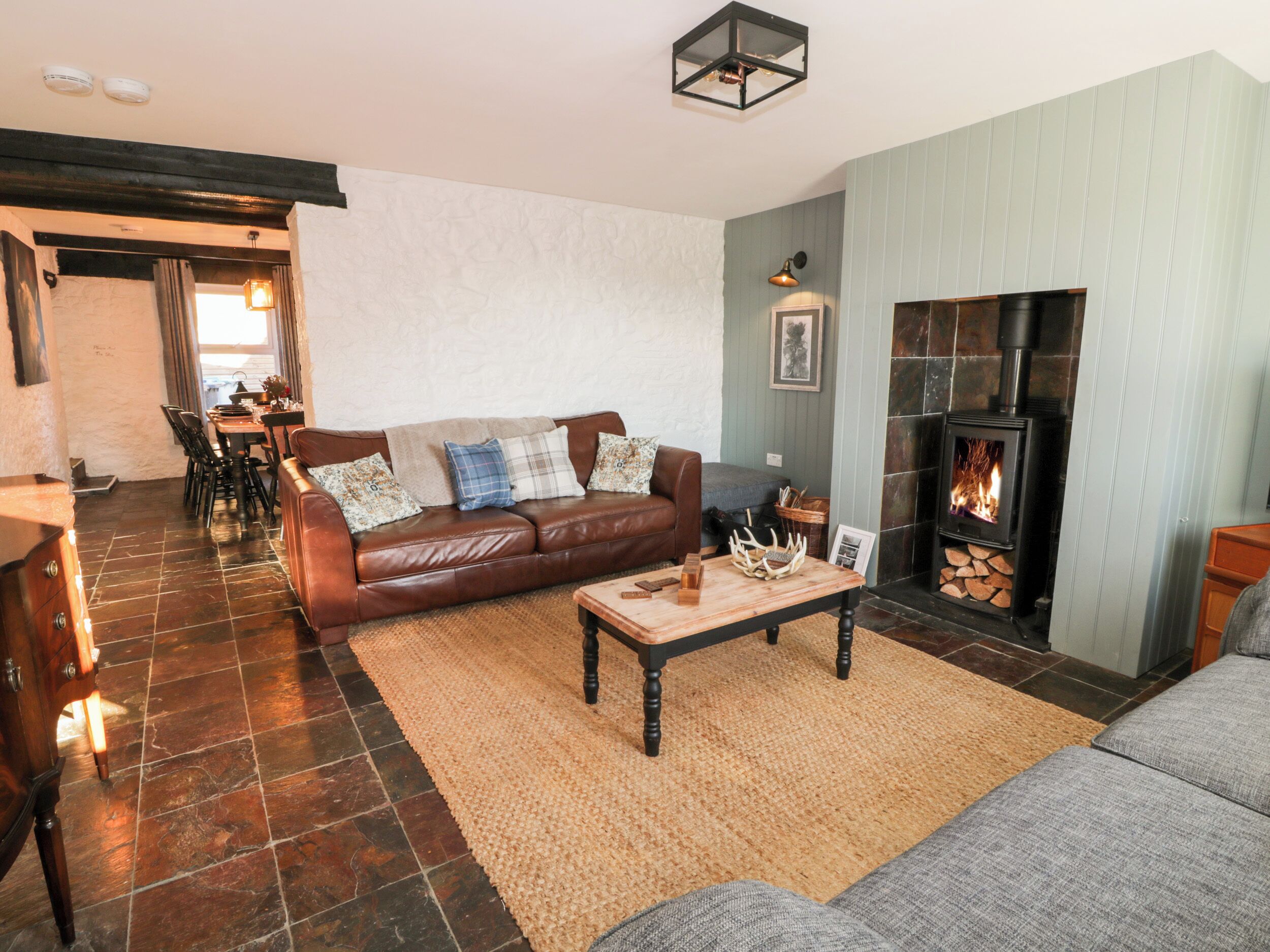 A cozy living room with a brown leather sofa, a wooden coffee table, and a stone fireplace.