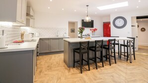 Una cocina moderna con una isla central, armarios grises y un refrigerador rojo.
