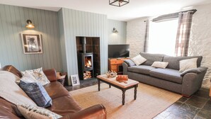 Un salón acogedor con chimenea, un sofá, un televisor y una pared de piedra.