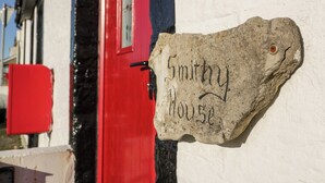 Un letrero de piedra con la inscripción 'Smithy House' adosado a la pared exterior de un edificio.