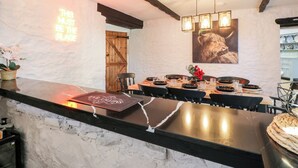 Un interior de restaurante con una barra de mármol, vigas de madera y un cuadro grande de un perro.