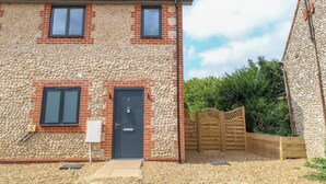 A two-story house with a red-tiled roof, a stone facade, and a wooden gate. - Henham 3 Bernaleen Cottages (King's Lynn)