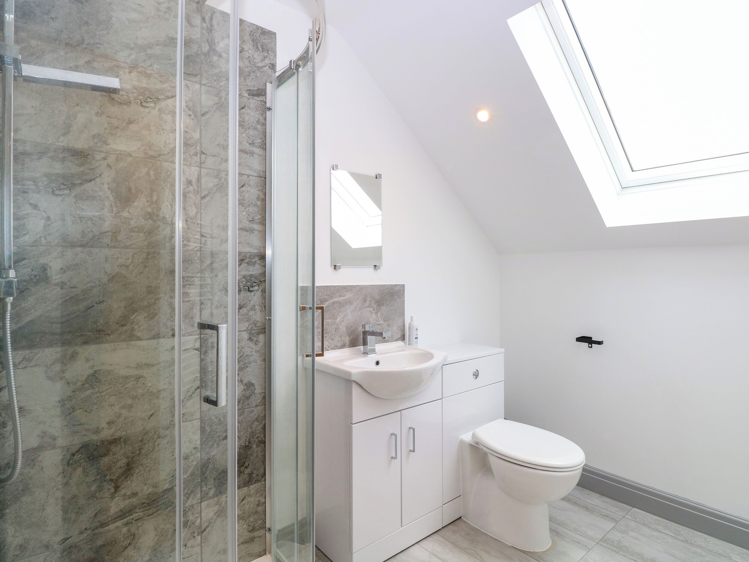 A modern bathroom with a glass shower enclosure, a white sink, and a toilet.