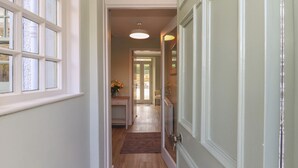 A hallway with a wooden floor, a door with a glass panel, and a window with frosted glass. - 30 Northgate (Peebles)
