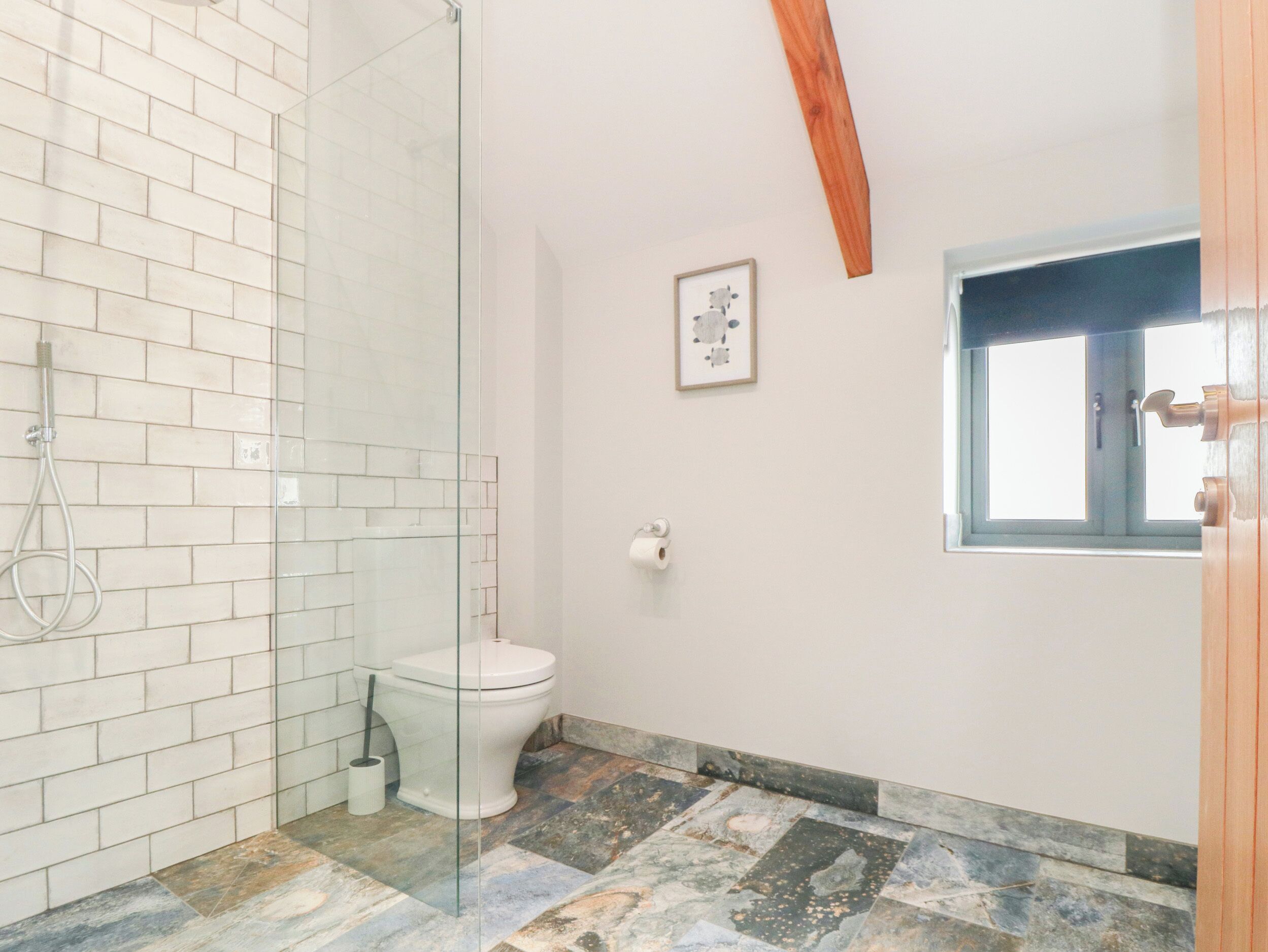 Un baño con cabina de ducha de vidrio, inodoro blanco y ventana con vistas.
