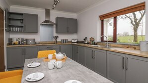 Een moderne keuken met grijze kastjes, een houten aanrecht en een eettafel gedekt voor vier personen.
