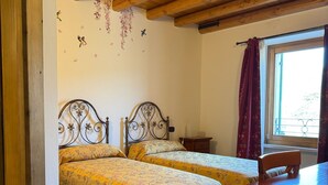 Quarto com duas camas, uma mesa de madeira e uma janela com cortinas.